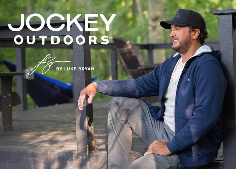 Luke Bryan wearing the outdoors collection standing by green wall