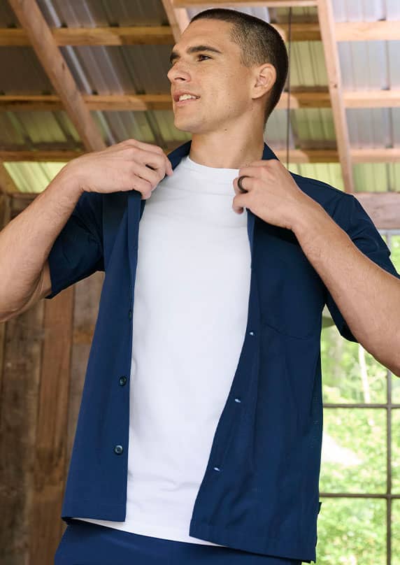 man putting on a button up over his underhsirt